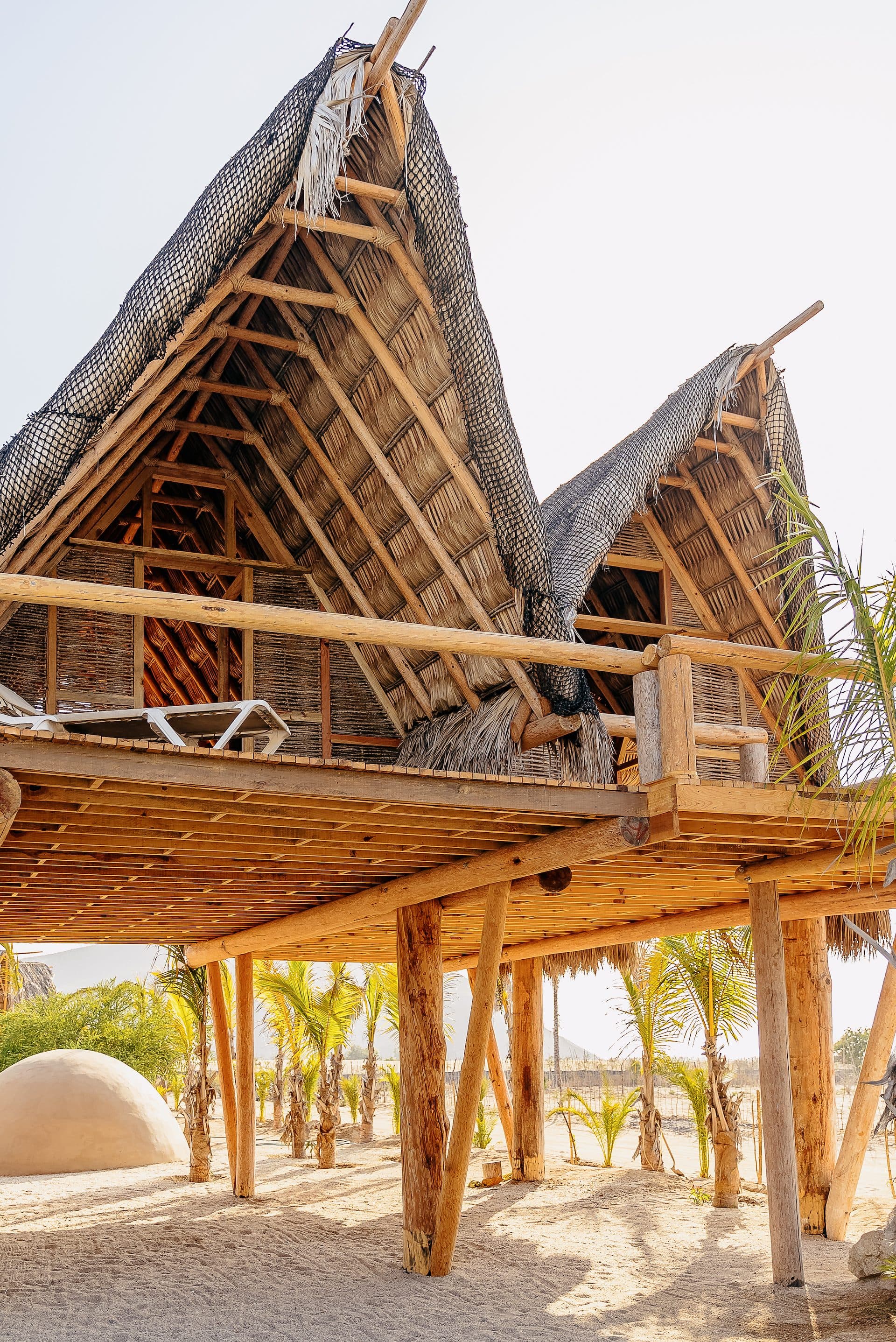 Elevated A-frame treehouse suites with thatched roofs